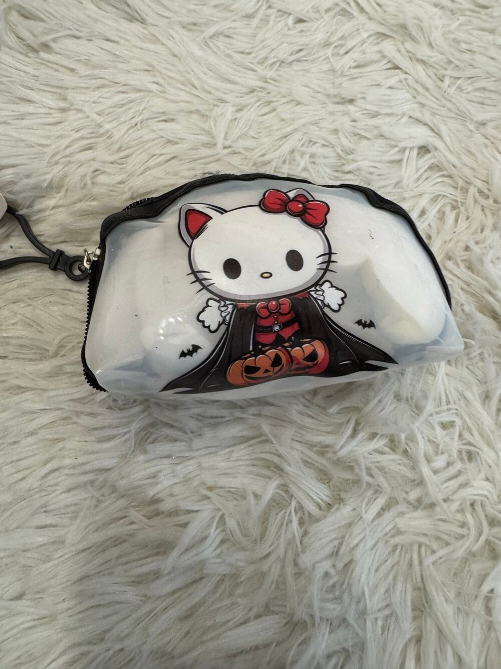 Hello Kitty Halloween coin purse keychain in a black cape holding pumpkins